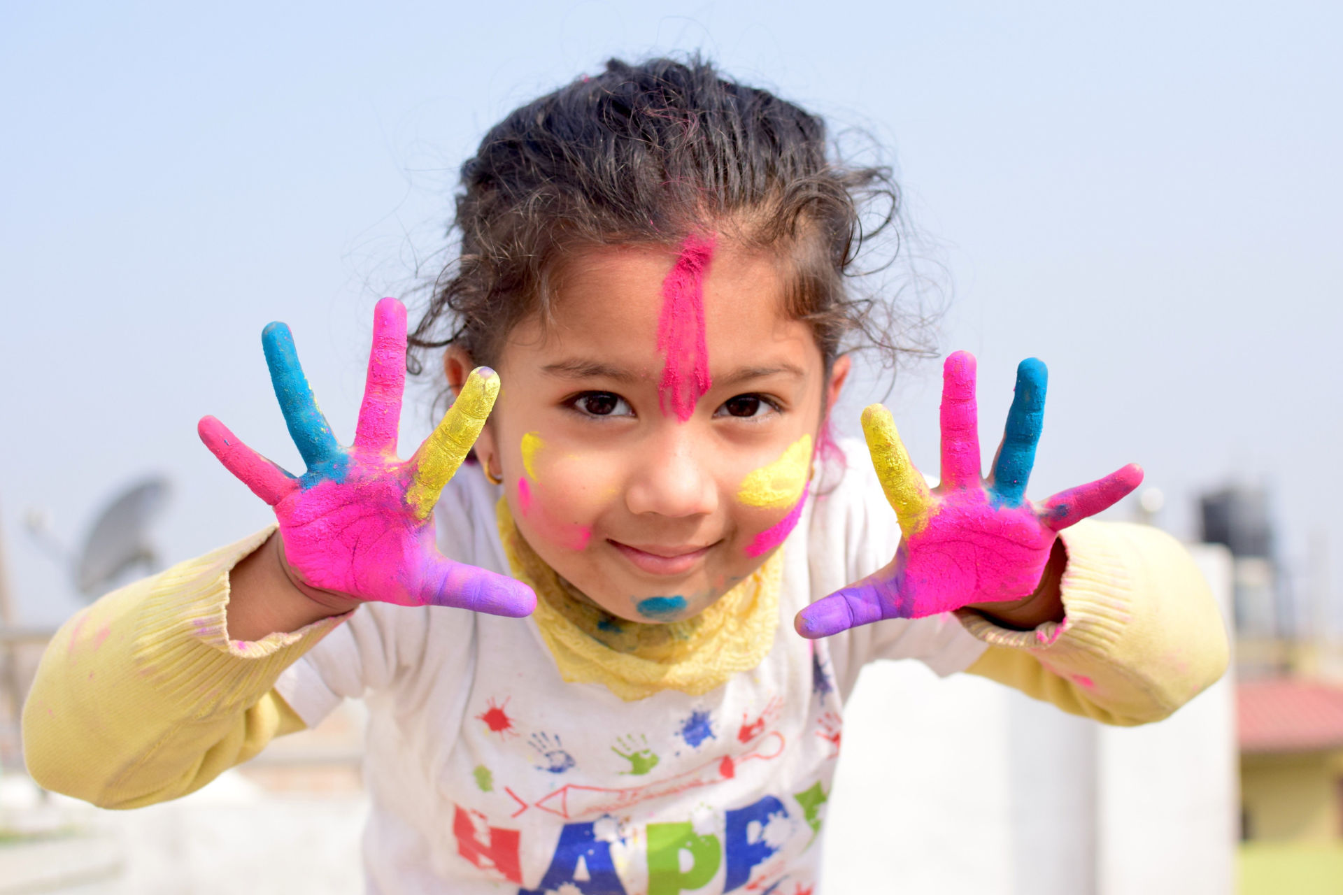 Une enfant montre ses mains pleines de peinture.