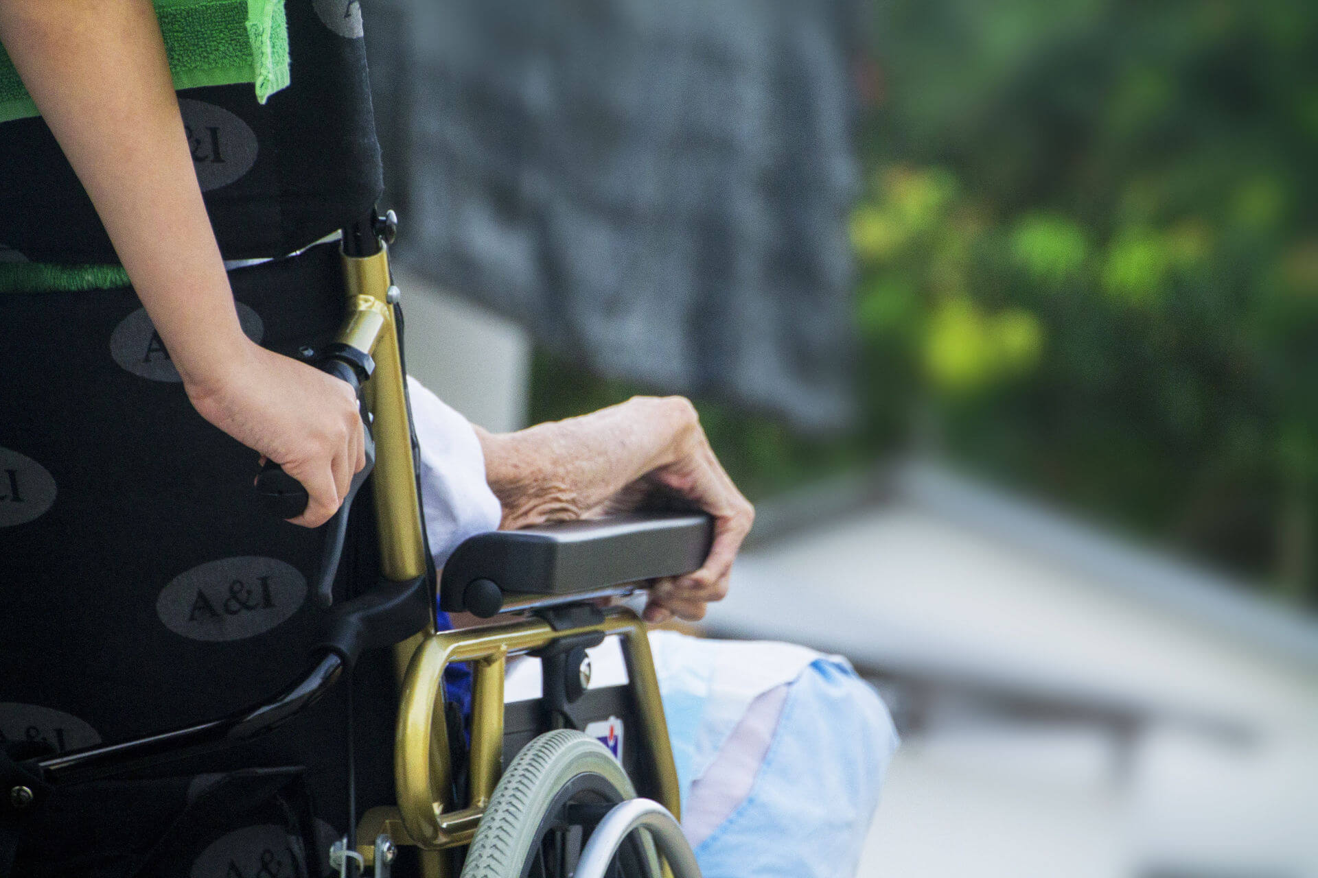 Une personne pousse un fauteuil roulant avec une personne âgée.