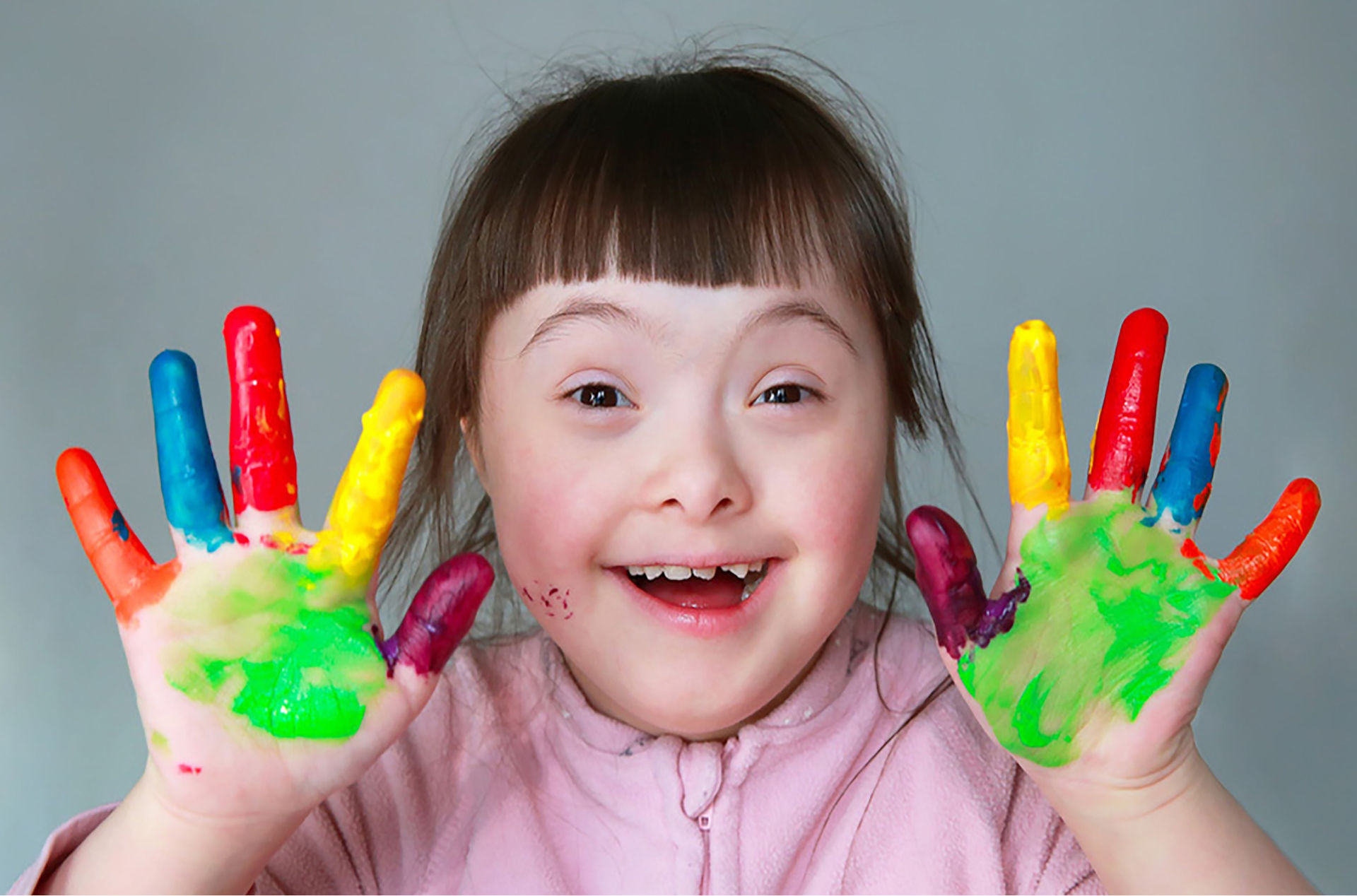 Une enfant montre ses doigts remplis de peinture.