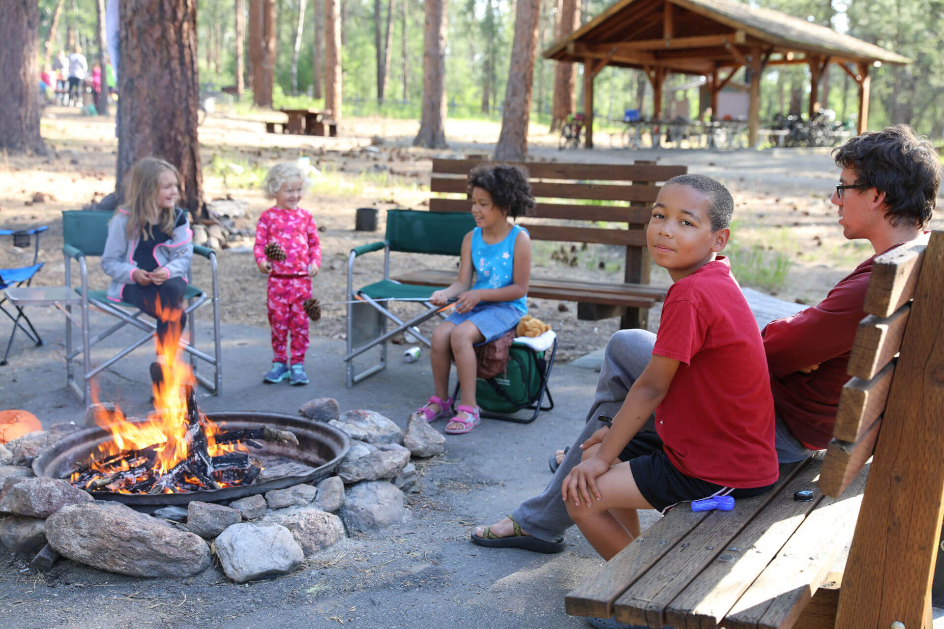 Des enfants et un animateur sont réunis autour d'un feu de camp.