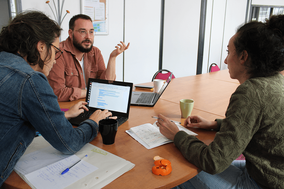 Trois personnes autour d'une table sont en formation.